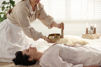 Woman undergoing singing bowl therapy lying on floor indoors