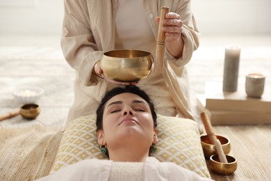 Photo of Woman undergoing singing bowl therapy lying on floor indoors