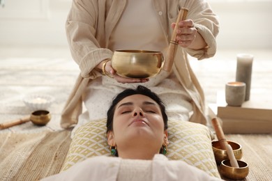 Photo of Woman undergoing singing bowl therapy lying on floor indoors