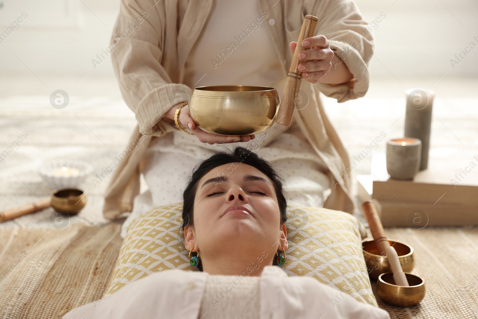 Photo of Woman undergoing singing bowl therapy lying on floor indoors