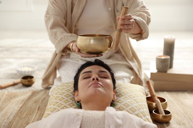 Woman undergoing singing bowl therapy lying on floor indoors