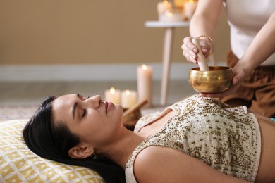 Woman undergoing singing bowl therapy lying on floor indoors