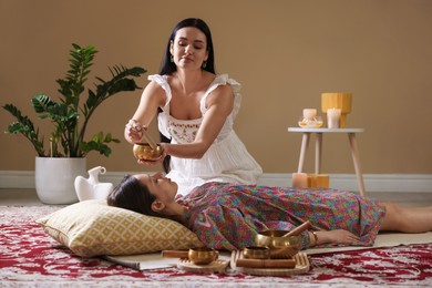 Woman undergoing singing bowl therapy lying on floor indoors