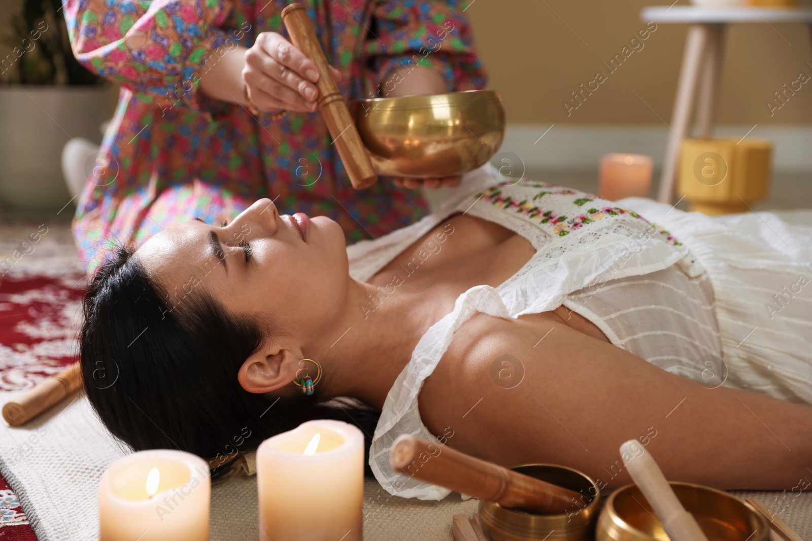 Photo of Woman undergoing singing bowl therapy lying on floor indoors