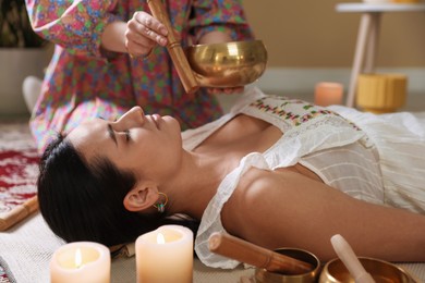 Woman undergoing singing bowl therapy lying on floor indoors