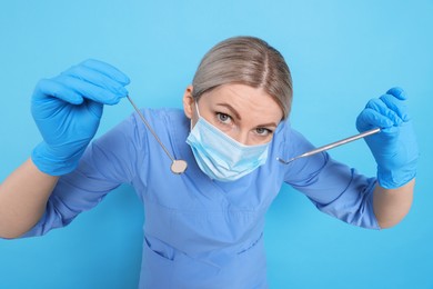 Professional dentist with tools on light blue background