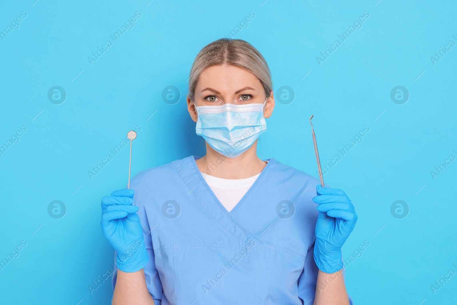 Photo of Professional dentist with tools on light blue background