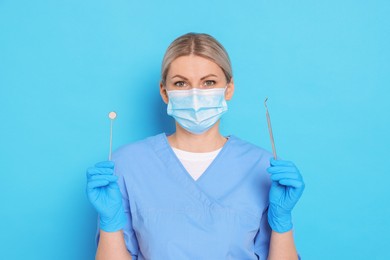 Professional dentist with tools on light blue background