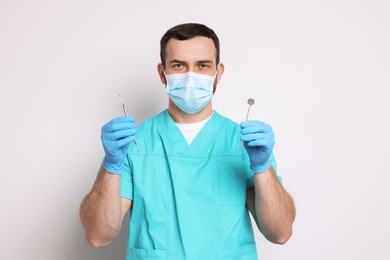 Professional dentist with tools on light background