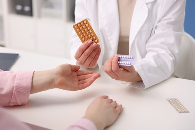 Gynecologist recommending contraceptive pills to woman in clinic, closeup