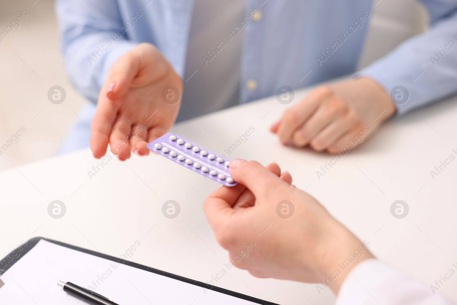 Photo of Gynecologist recommending contraceptive pills to woman in clinic, closeup