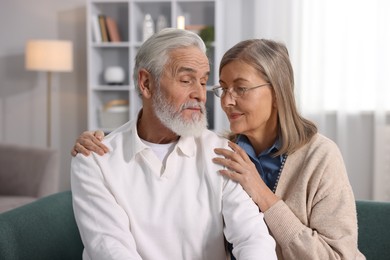 Cute elderly couple on sofa at home