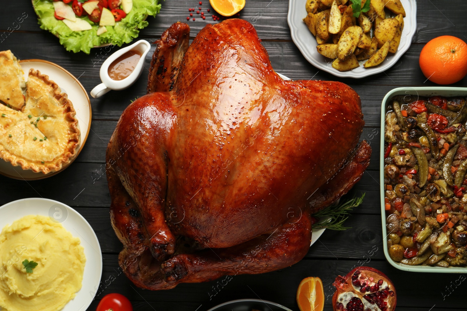 Photo of Whole baked turkey and other dishes served on black wooden table, flat lay