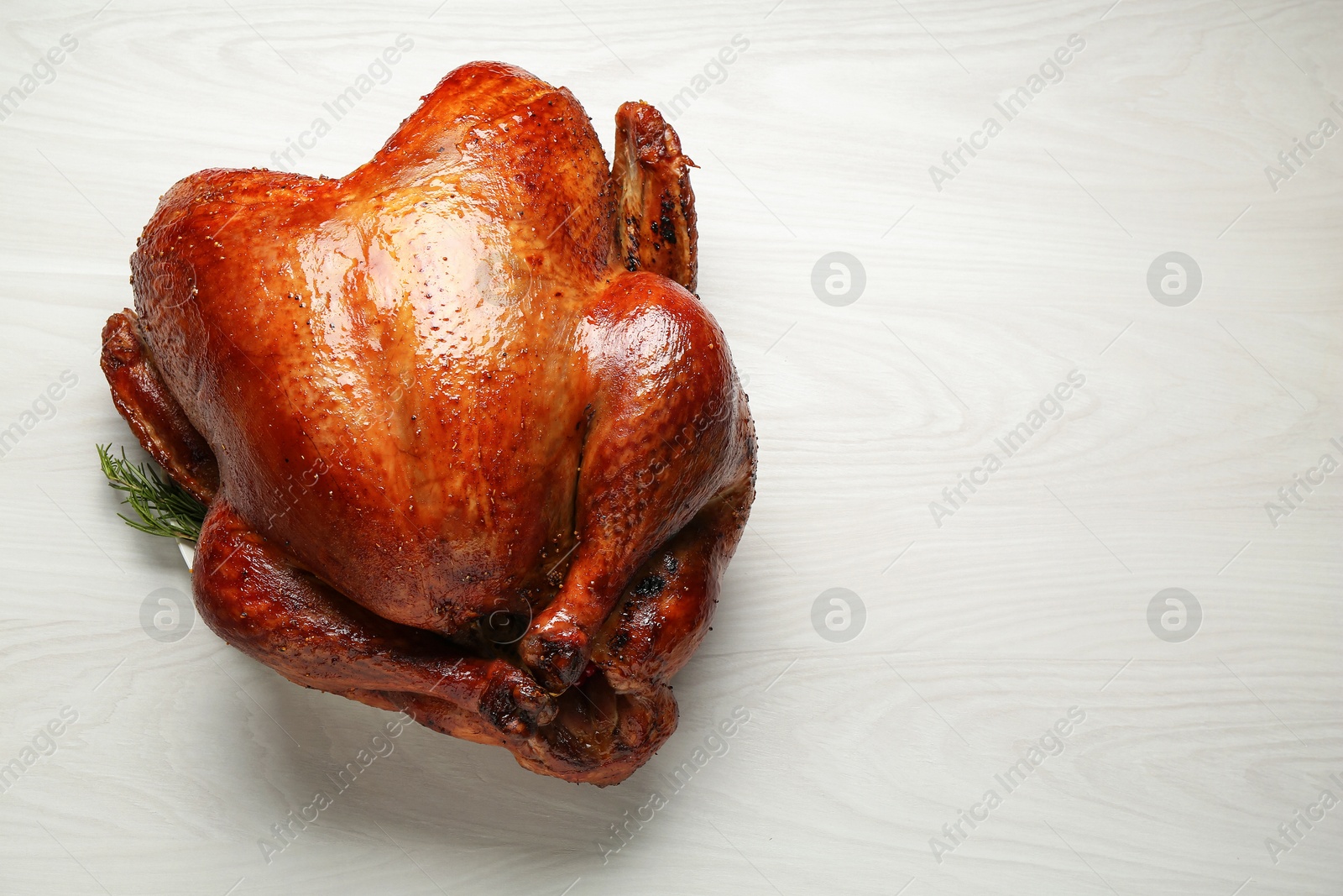 Photo of Whole baked turkey on light wooden table, top view. Space for text