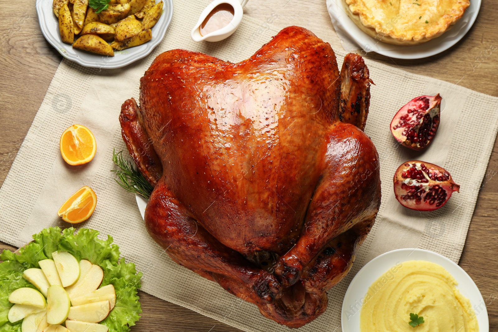 Photo of Whole baked turkey and other dishes served on wooden table, flat lay