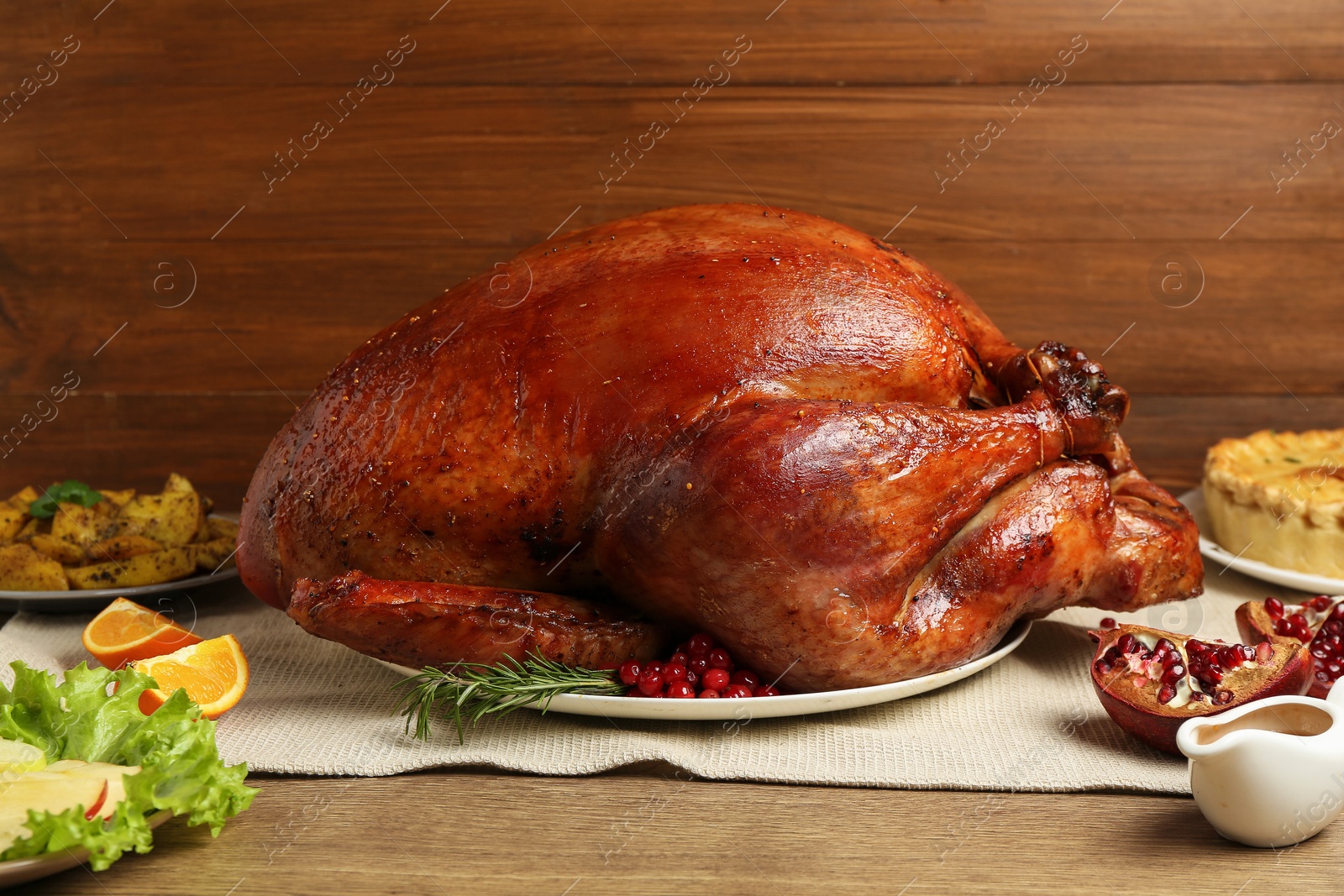 Photo of Whole baked turkey and other dishes served on wooden table