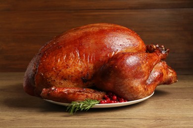 Whole baked turkey with cranberries and rosemary on wooden table, closeup