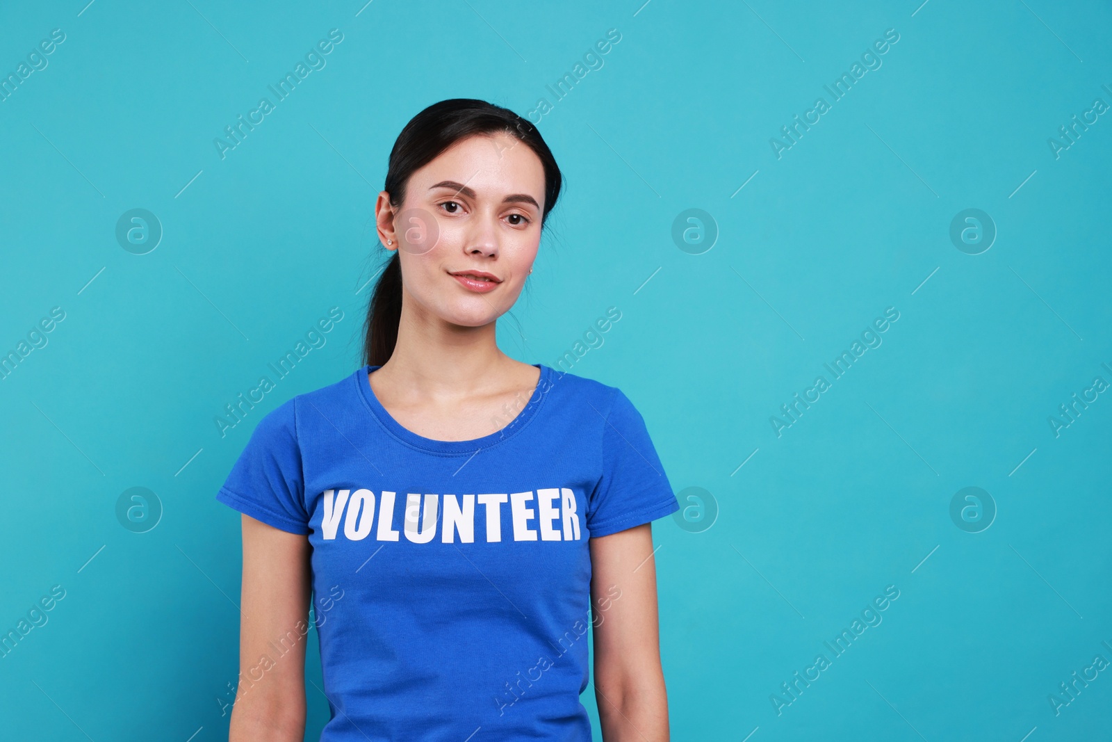 Photo of Young beautiful volunteer wearing t-shirt with printed word on light blue background. Space for text