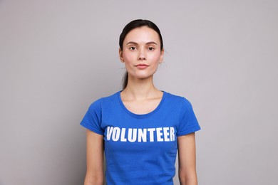 Photo of Young beautiful woman wearing t-shirt with printed word Volunteer on grey background