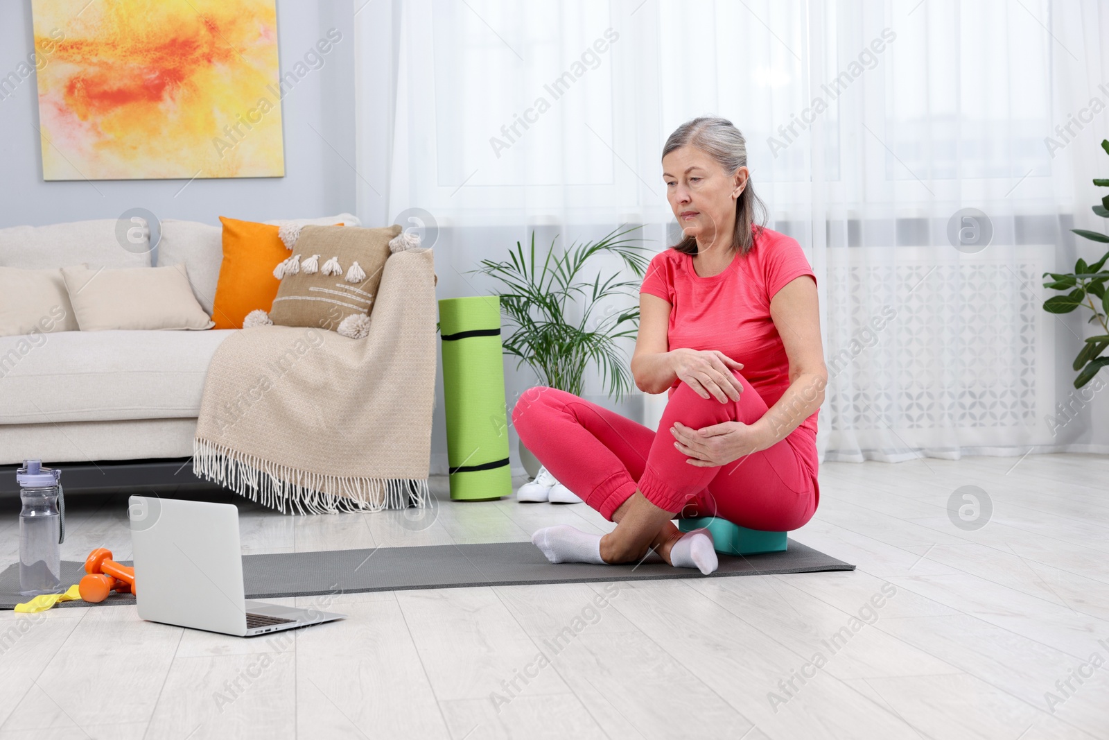 Photo of Elderly woman looking video tutorial by laptop at home. Healthy lifestyle