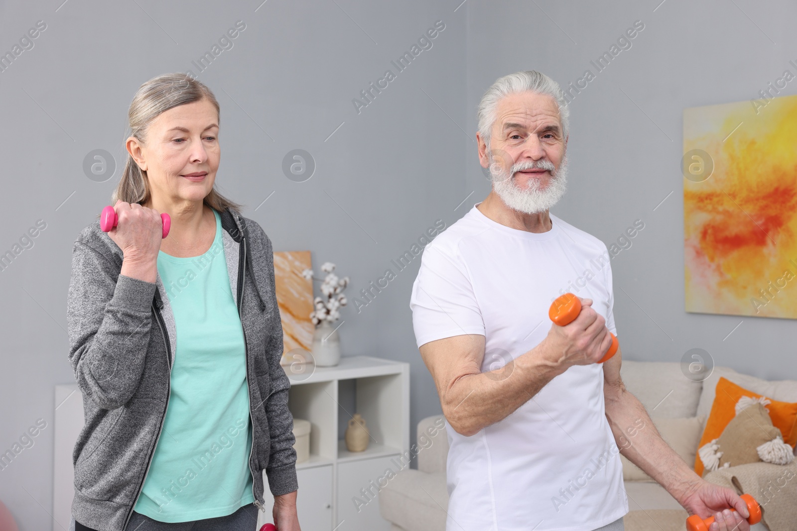 Photo of Elderly couple exercising with dumbbells at home