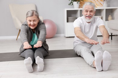 Photo of Smiling elderly couple exercising at home. Healthy leisure