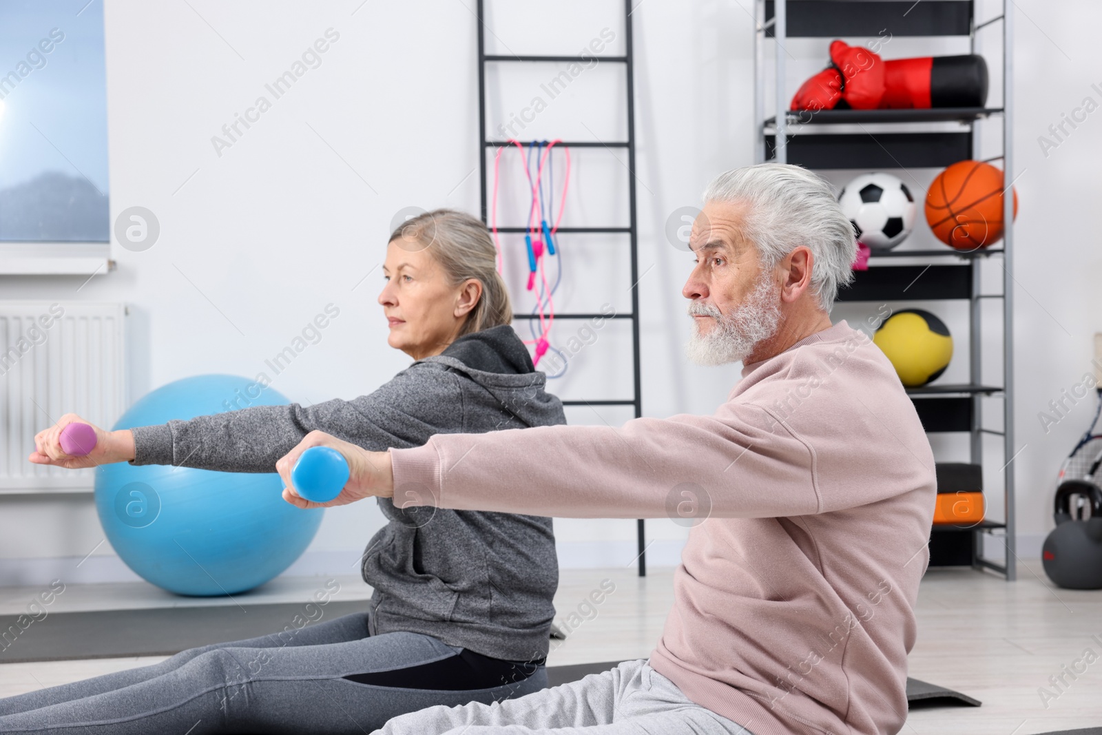 Photo of Elderly couple exercising with dumbbells at home