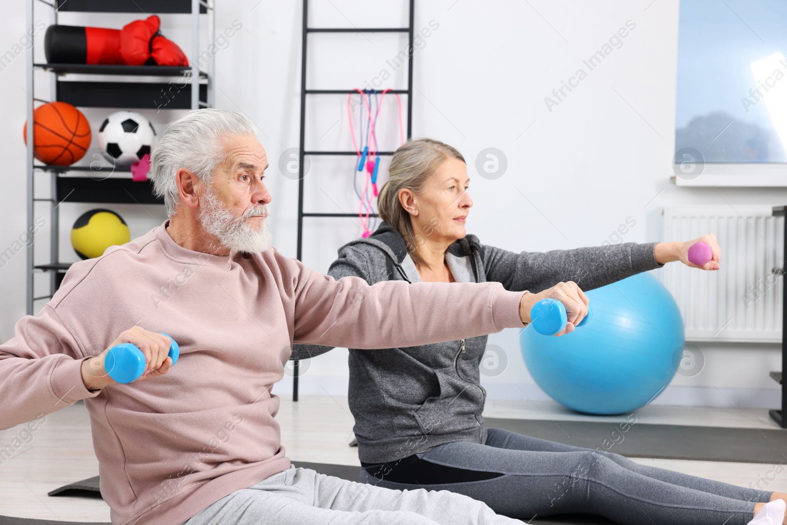 Photo of Elderly couple exercising with dumbbells at home