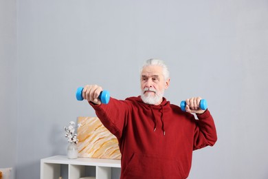 Elderly man exercising with dumbbells at home