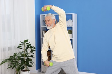 Elderly man exercising with dumbbells at home