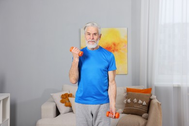 Elderly man exercising with dumbbells at home