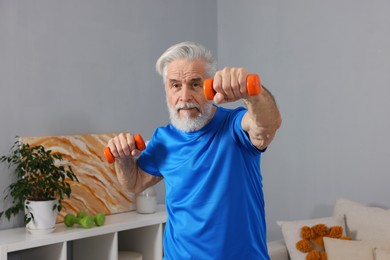 Photo of Elderly man exercising with dumbbells at home