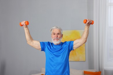 Elderly man exercising with dumbbells at home