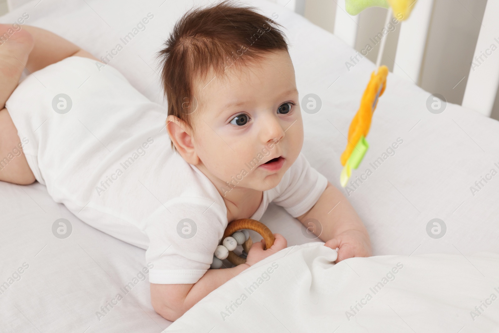 Photo of Cute little baby in crib with cot mobile at home