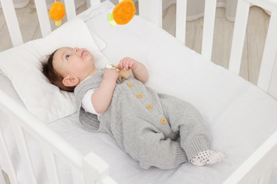 Photo of Cute little baby in crib with cot mobile at home