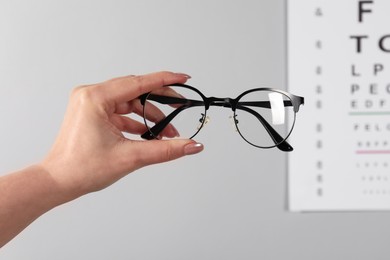 Photo of Woman holding glasses on grey background, closeup