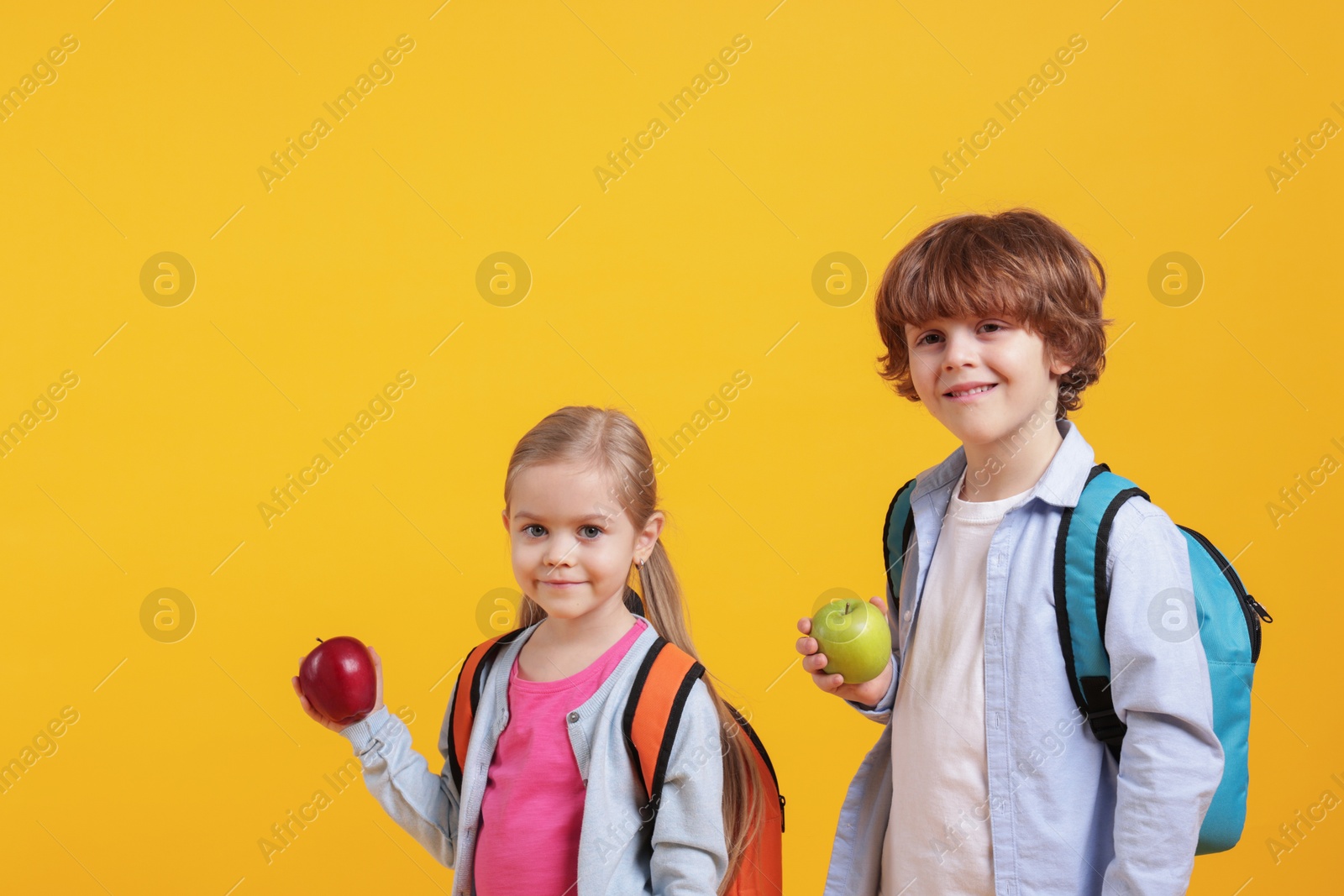 Photo of School children with apples on orange background. Space for text