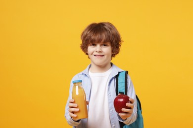 Photo of Little boy with apple and drink on orange background