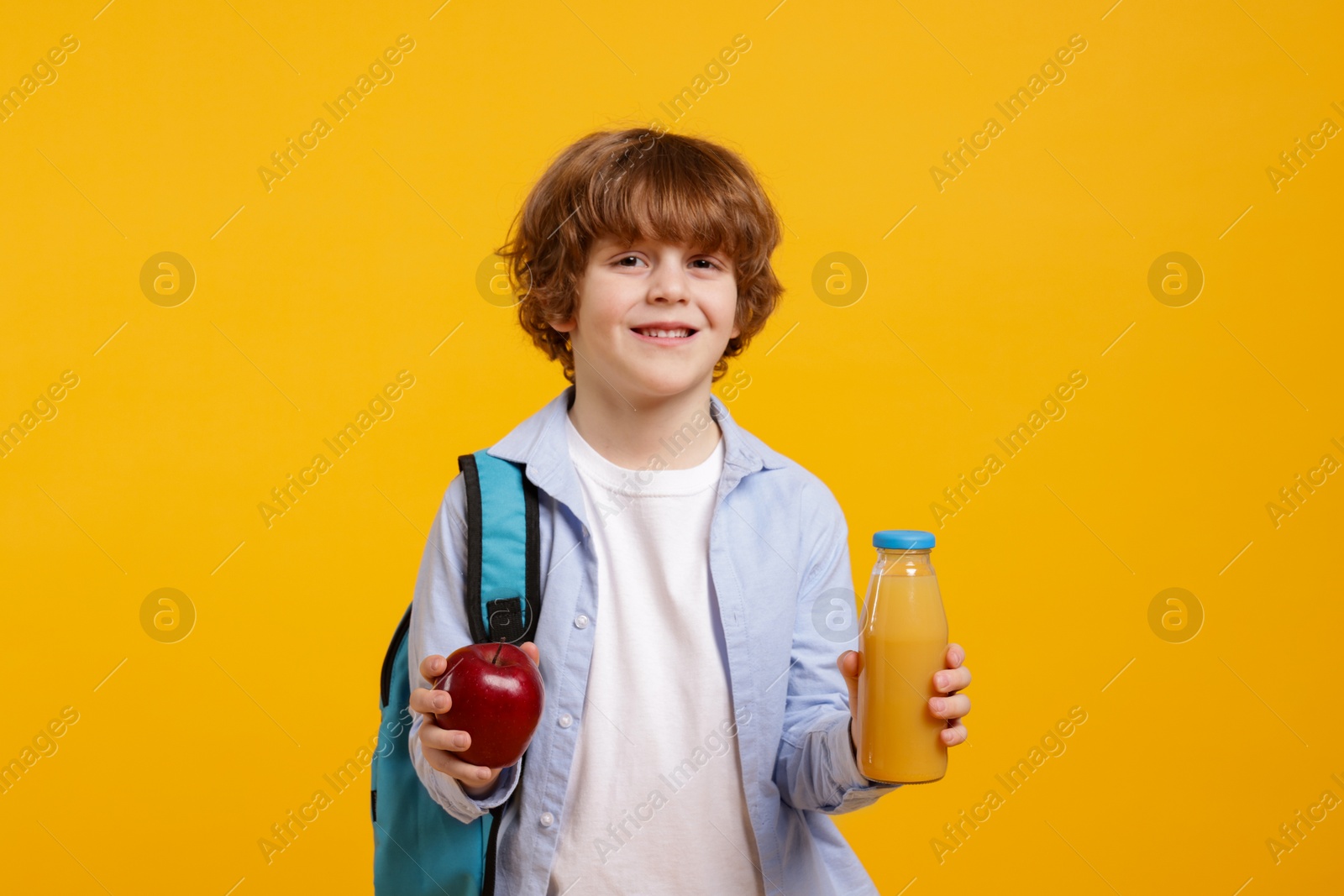 Photo of Little boy with apple and drink on orange background