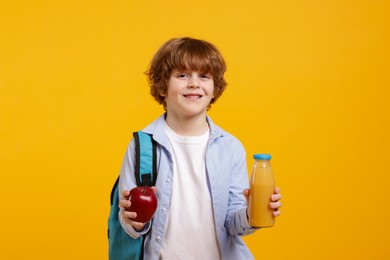 Little boy with apple and drink on orange background