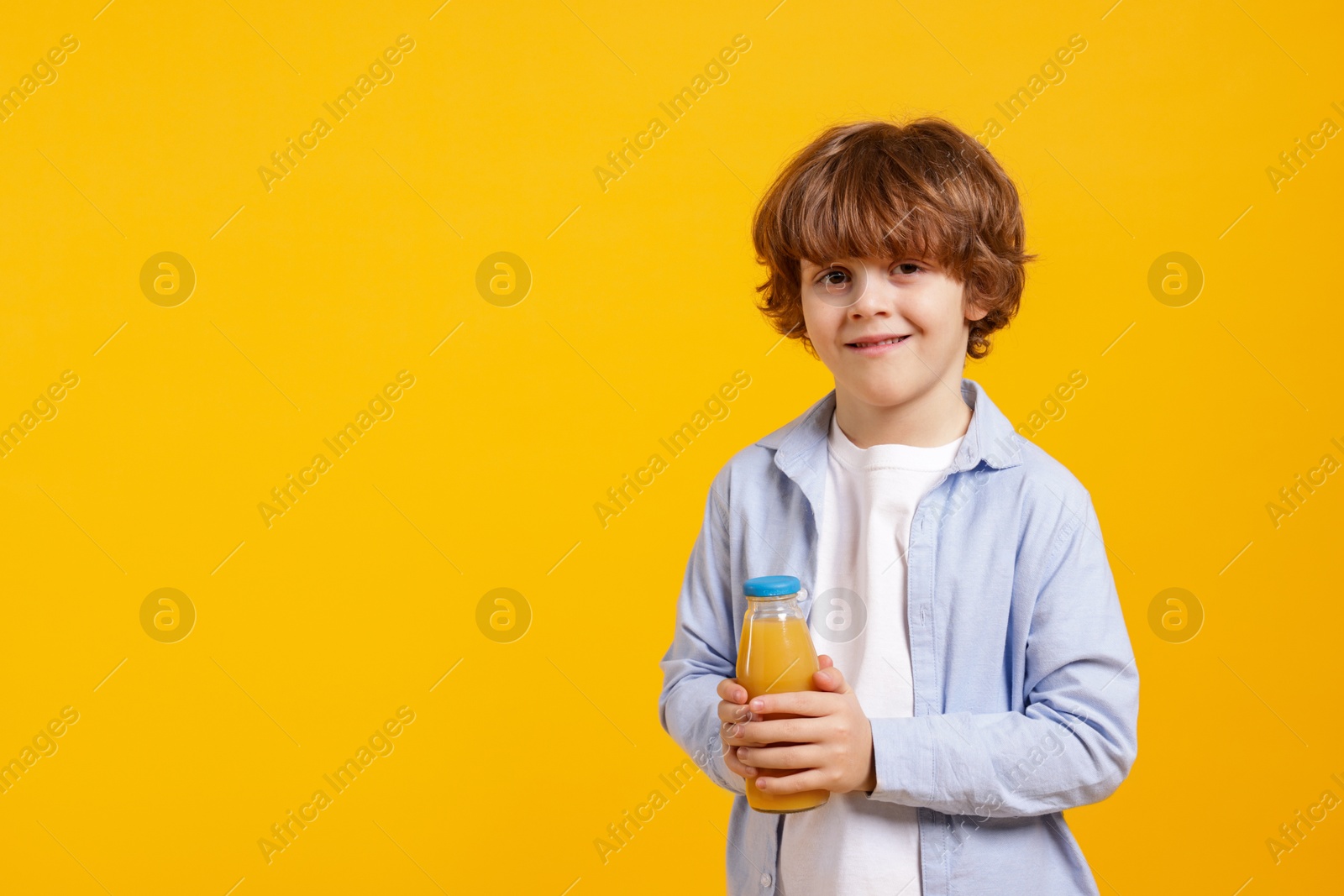 Photo of Little boy with drink on orange background. Space for text