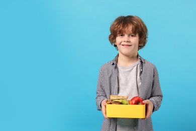 Photo of Cute little boy with lunch box on light blue background. Space for text