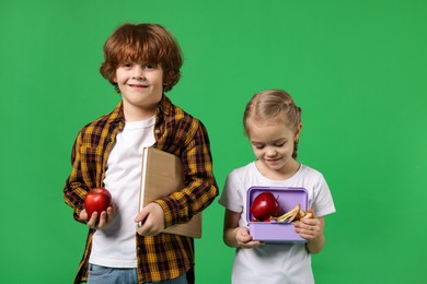 Cute little children with lunch on green background