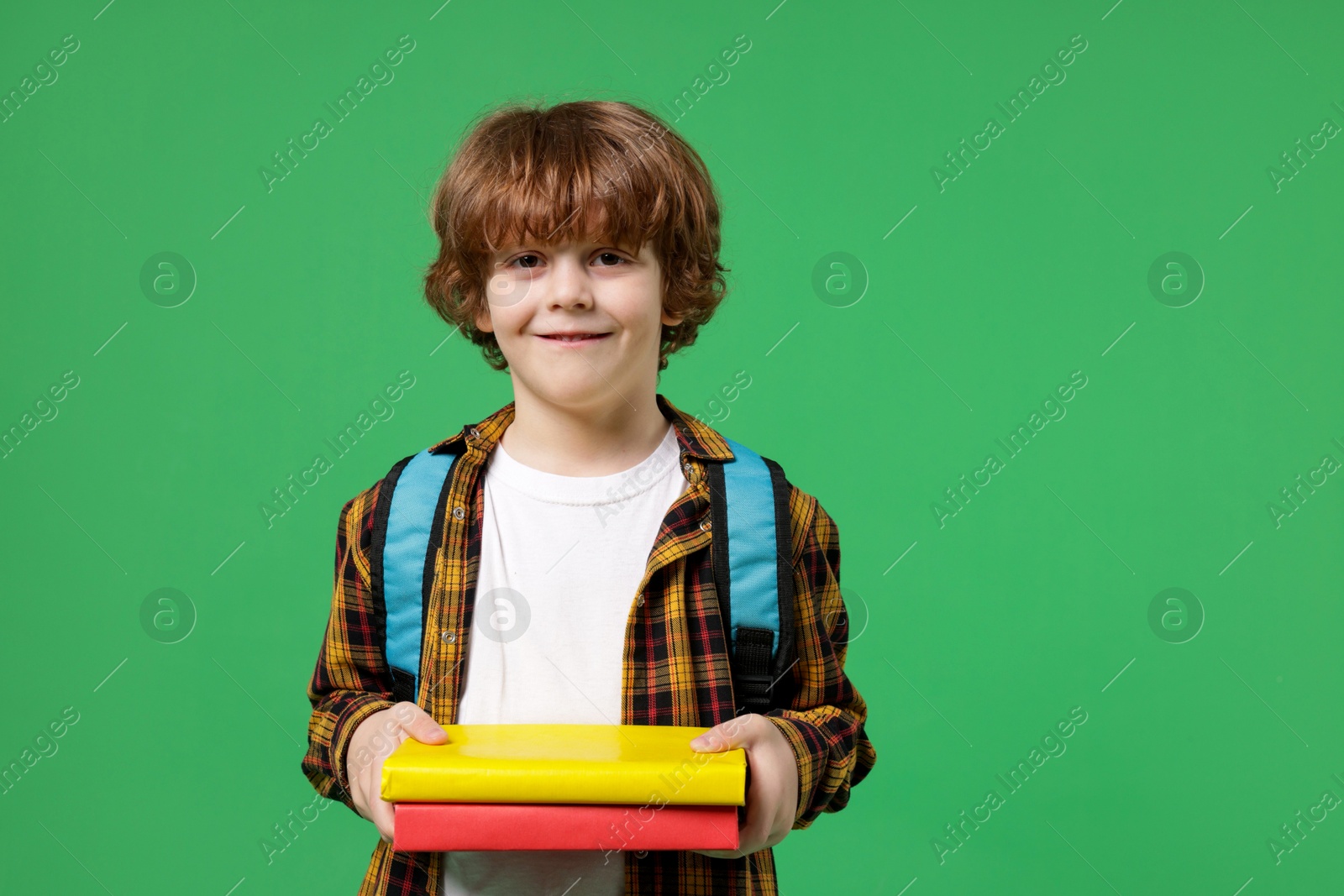 Photo of Cute little boy with backpack and books on green background. Space for text