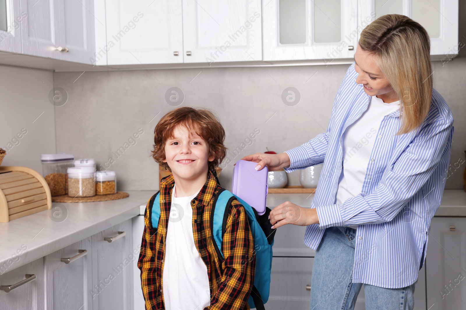 Photo of Mother packing her son's lunch in kitchen