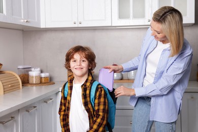 Mother packing her son's lunch in kitchen