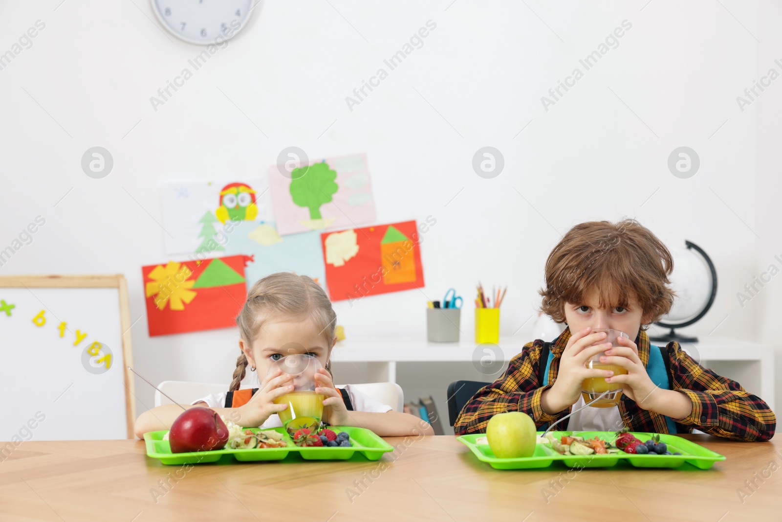 Photo of Cute little children eating lunch at wooden table in school