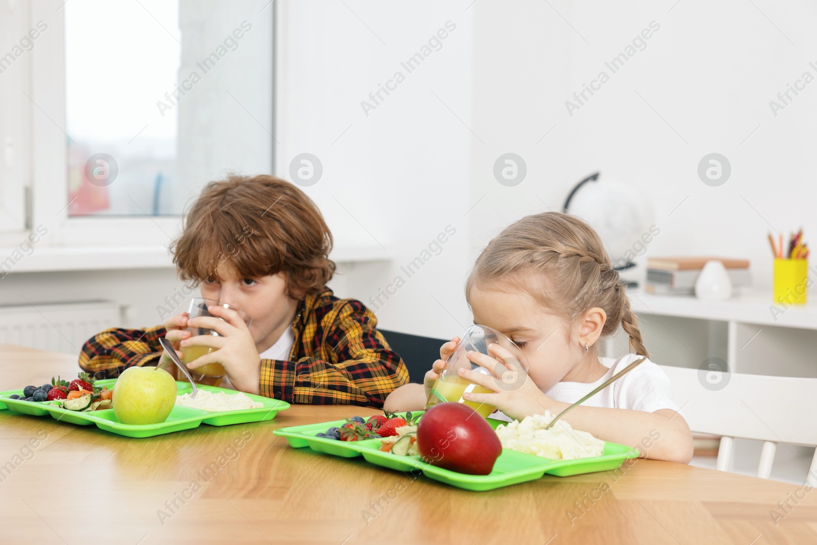 Photo of Cute little children eating lunch at wooden table in school