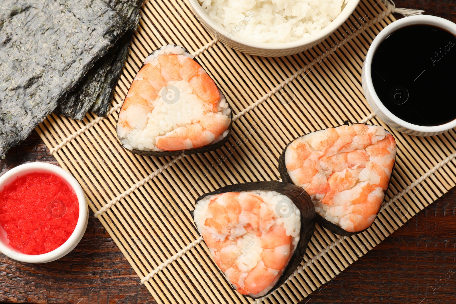 Photo of Tasty onigiri (Japanese rice balls) with shrimps served on wooden table, flat lay