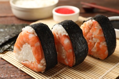 Photo of Tasty onigiri (Japanese rice balls) with shrimps on wooden table, closeup